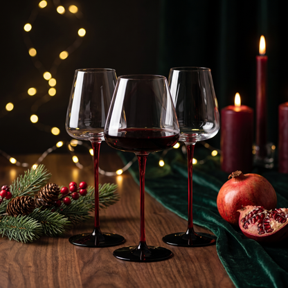 Three Scarlet Stem crystal glasses on a dark Christmas table with pine, pomegranate and fairy lights