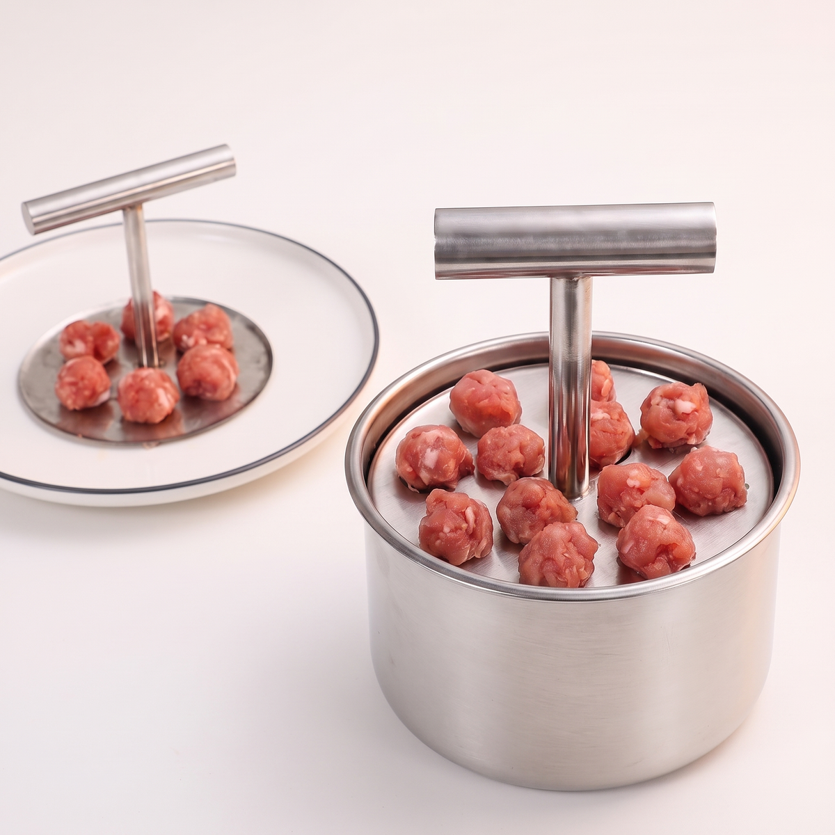 The press beside a plate of released meatballs, on a light ground