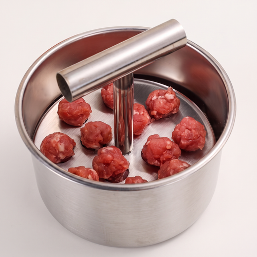 Piston Meatball Press loaded with mince, on a light ground